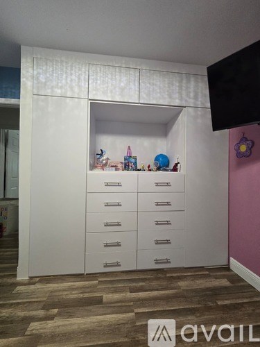 A room with a white cabinet and a television on the wall.