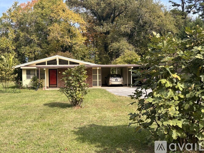 A house with a red door is surrounded by greenery.
