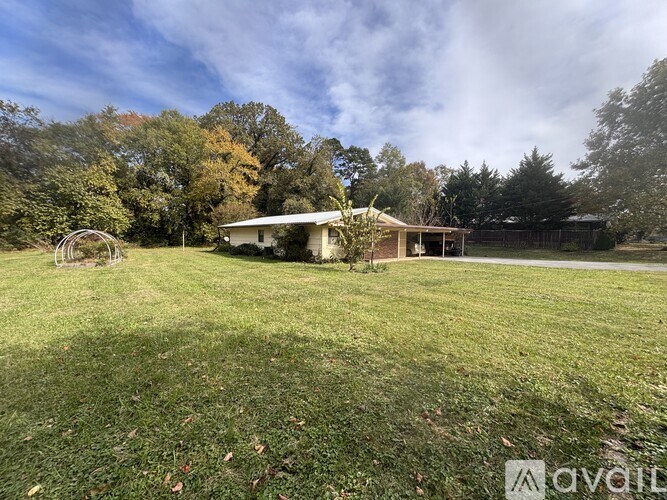 A house with a white roof is surrounded by a grassy field and trees.