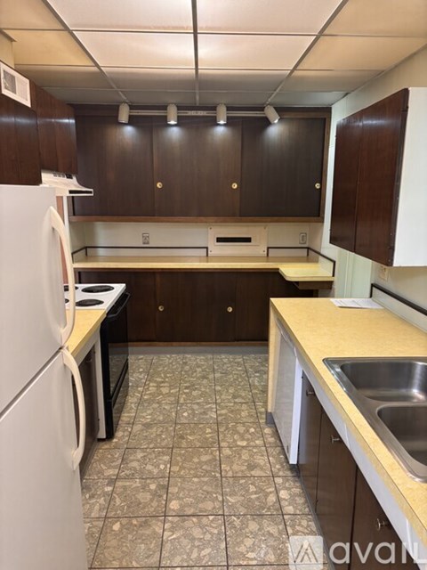 A kitchen with a white fridge and brown cabinets.