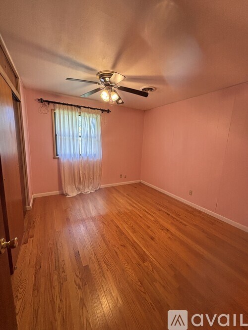 A room with a ceiling fan and wooden flooring.