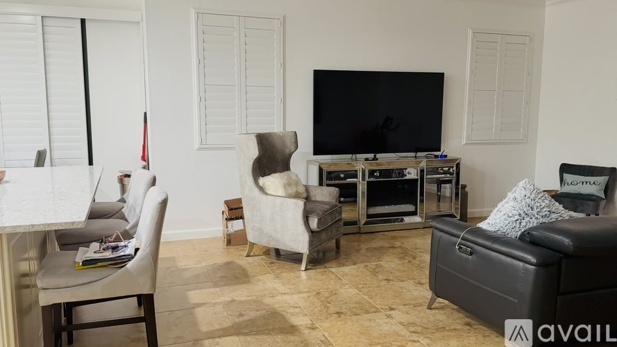 A living room with a television, chairs, and a couch.