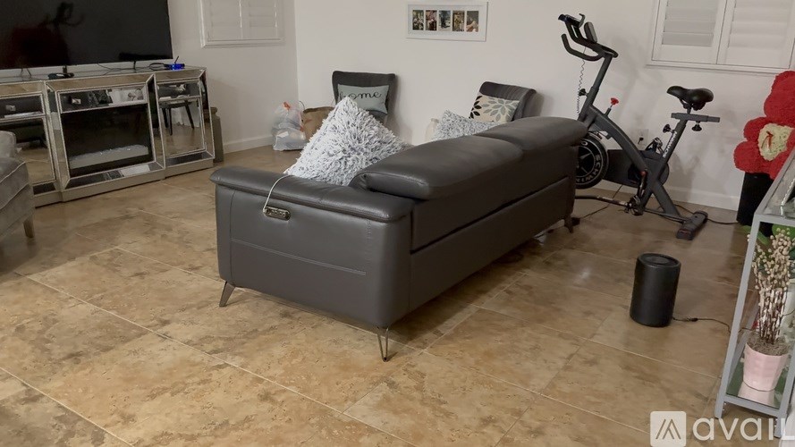 A grey couch with a pillow on it in a room with exercise equipment.