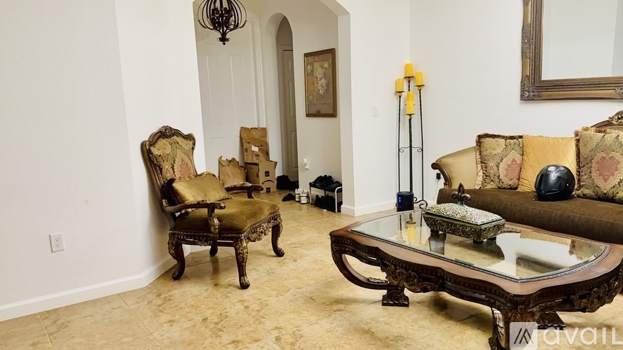 A living room with a brown sofa, a glass coffee table, and a chandelier.