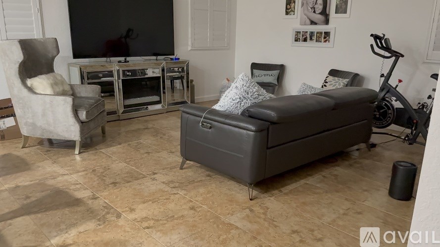 A living room with a grey sofa, a white chair, and a TV.