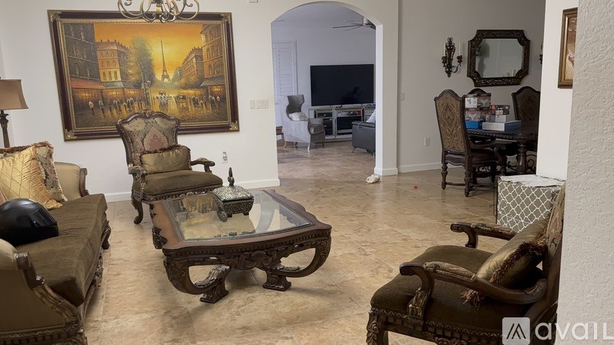A living room with a large painting on the wall and a chandelier hanging from the ceiling.