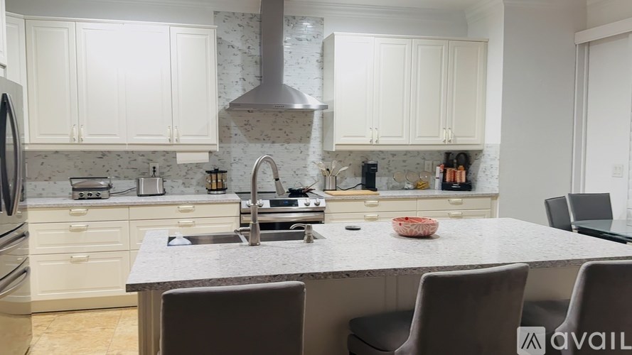 A modern kitchen with white cabinets and a marble countertop.