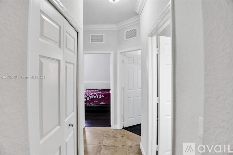A hallway with white doors and a tiled floor.