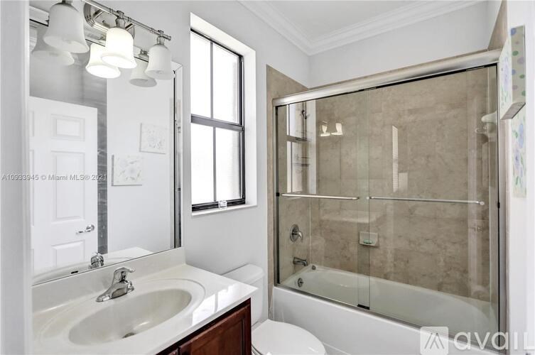A modern bathroom with a glass shower enclosure and a white sink.