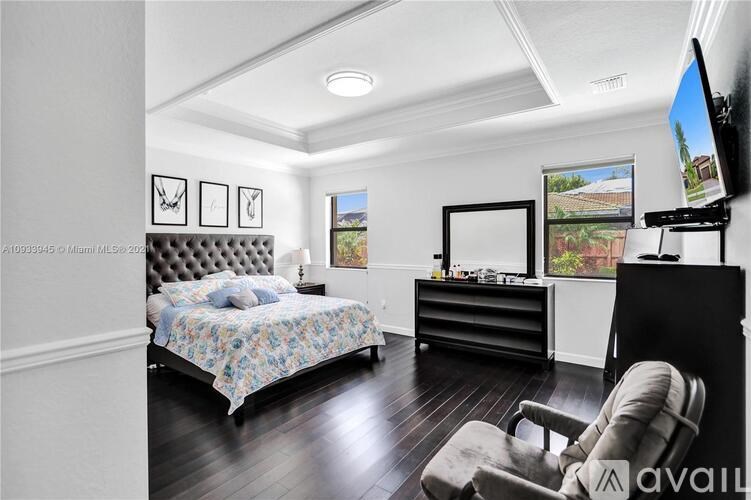 A bedroom with a bed, chair, and a television.