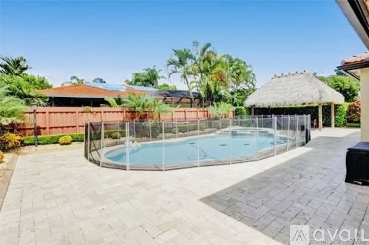 A backyard with a pool and a thatched roof structure.