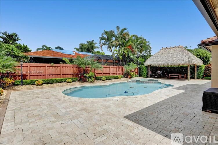 A backyard with a pool and a thatched roof gazebo.