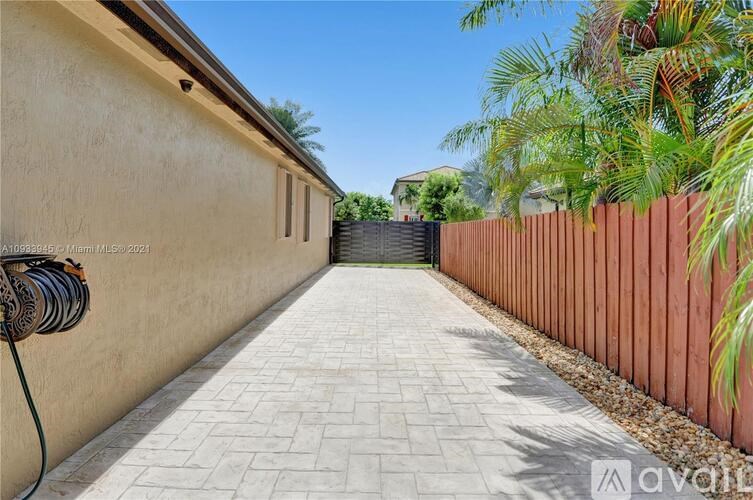 A long, narrow walkway with a wooden fence on one side and a wall on the other.