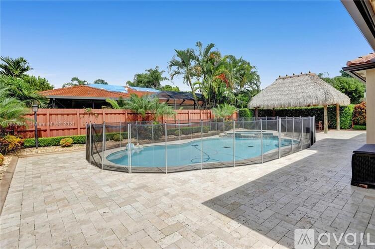 A backyard with a pool and a thatched roof structure.