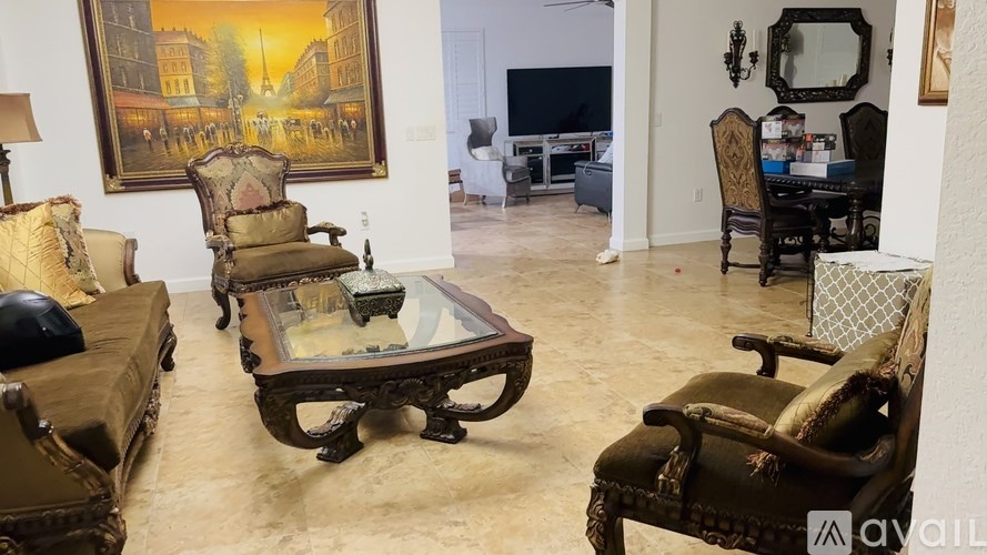 A living room with a large painting on the wall and a glass coffee table in the center.