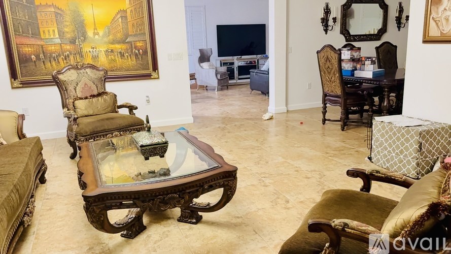 A living room with a large coffee table and a painting on the wall.