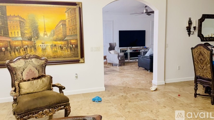 A painting of a street scene hangs on a wall above a chair.