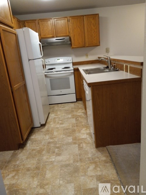 A kitchen with a white refrigerator, stove, and sink.