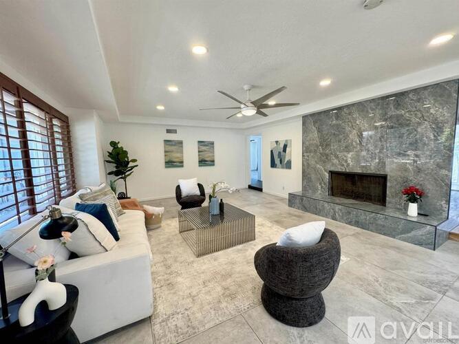 A living room with a fireplace and a ceiling fan.