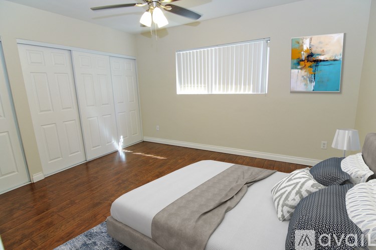 A bedroom with a bed, pillows, and a ceiling fan.