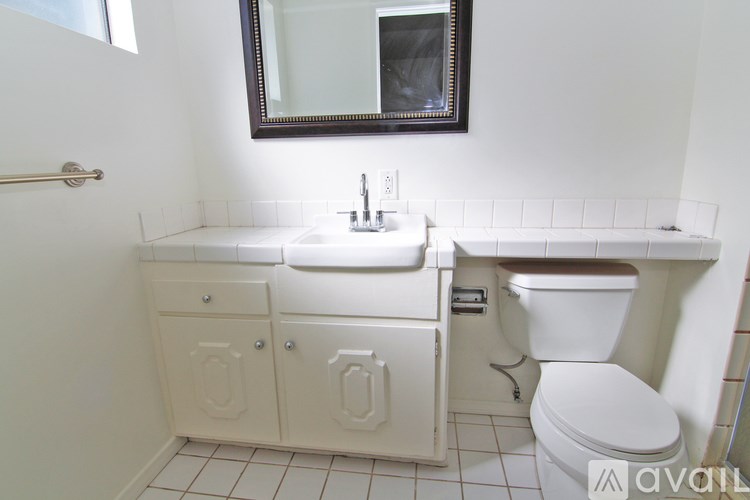 A white bathroom with a toilet, sink, and mirror.