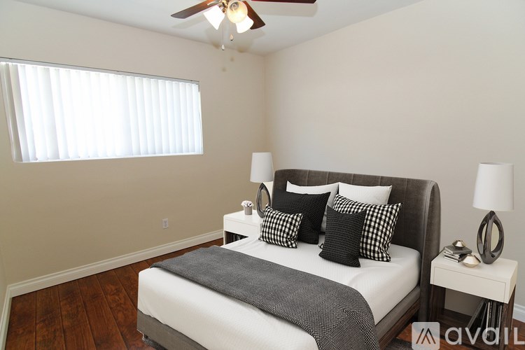 A bedroom with a bed, nightstand, and window with blinds.