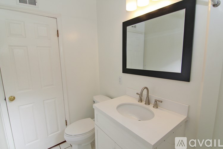 A white bathroom with a toilet, sink and mirror.