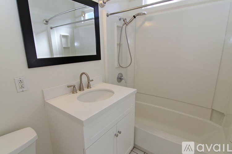A white bathroom with a sink, mirror, and bathtub.