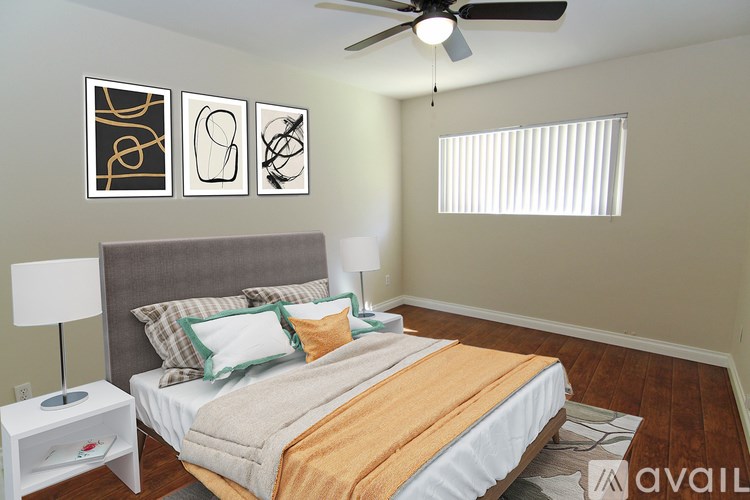 A bedroom with a bed, lamp, and artwork on the wall.