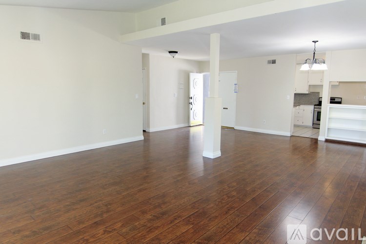 A spacious room with wooden floors and white walls.