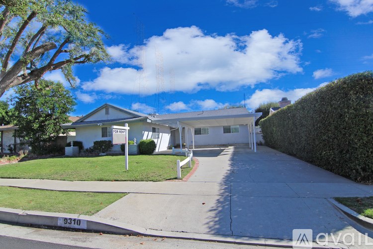 A house with a white fence and a tree in front of it.
