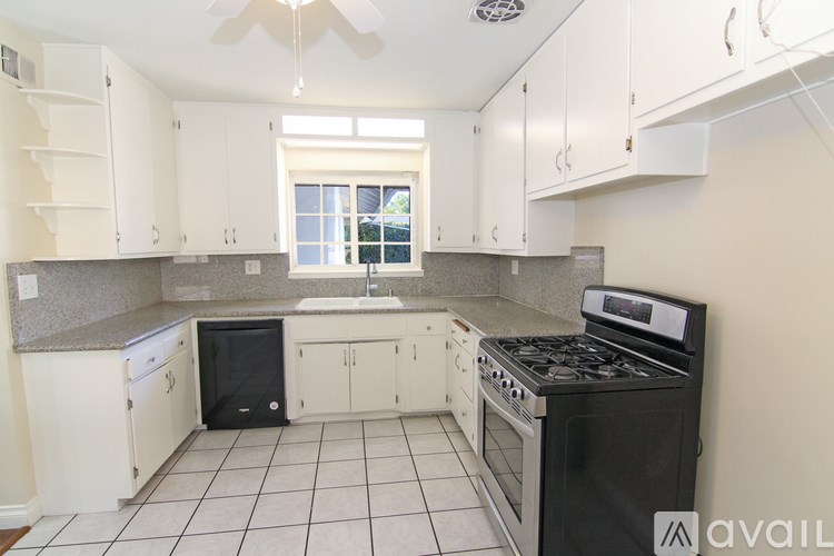 A kitchen with white cabinets and black appliances.