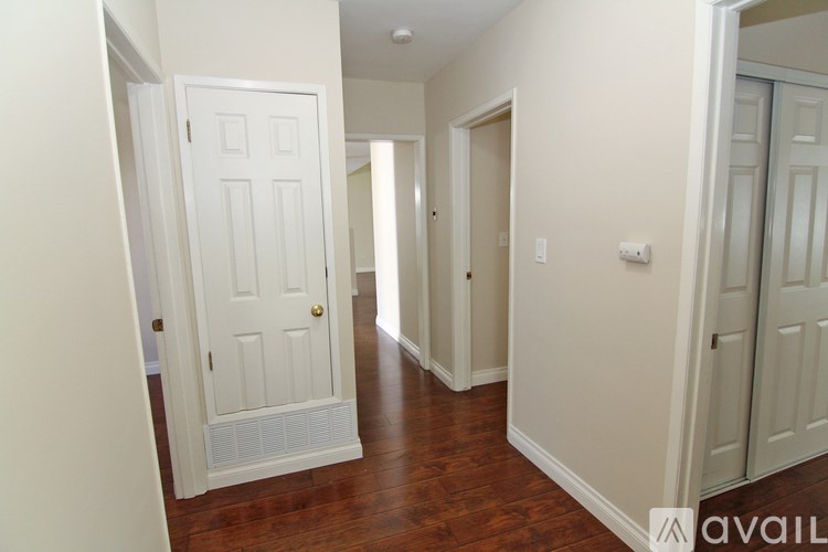 A hallway with a white door and a wooden floor.