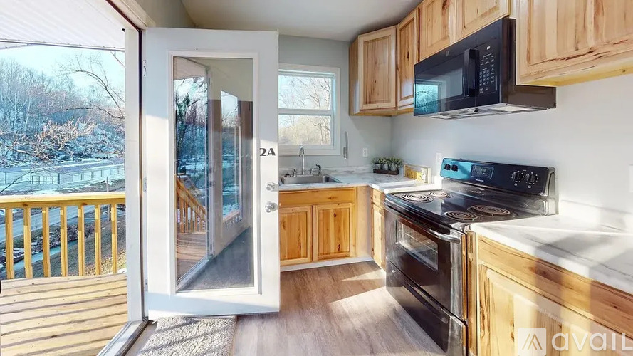 A kitchen with wooden cabinets and a black microwave above the stove.