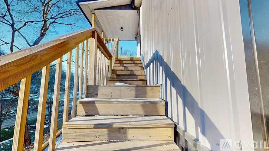 A wooden staircase with a railing leads up to a white building.