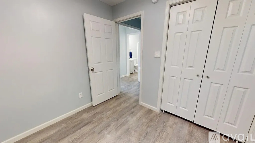 A room with a white door and a white cabinet with a mirror on top.