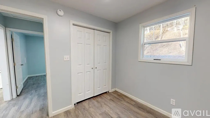 A room with a white door and a window with a view of a snowy landscape outside.