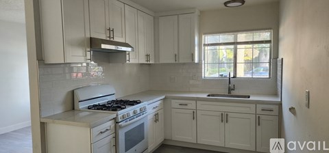 A kitchen with white cabinets and a stove top oven.
