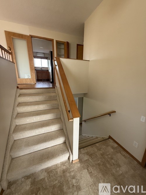 A staircase with a wooden handrail and a carpeted runner.