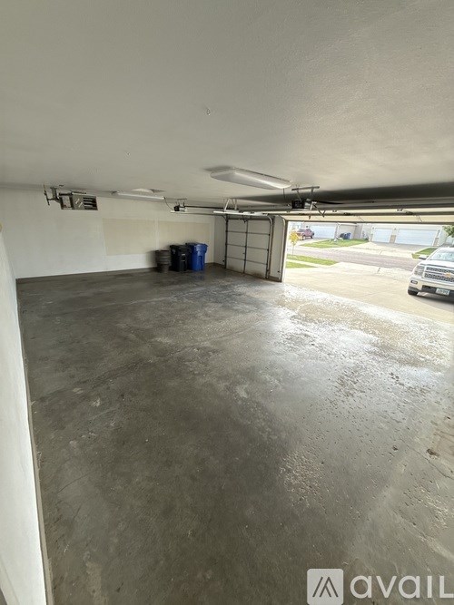 A large empty garage with a white wall and a door leading outside.