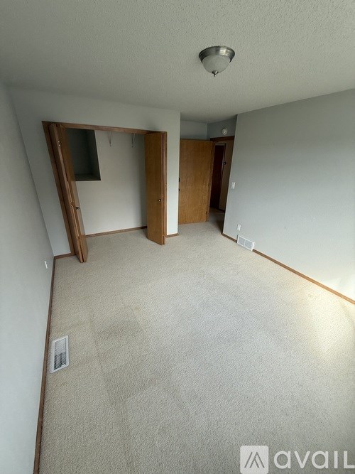 A room with a carpeted floor, a door, and a mirror on the wall.