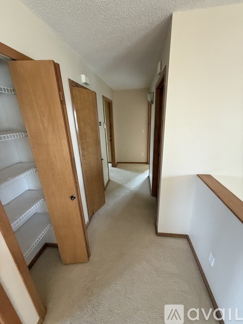 A hallway with a white carpet and a white wall.
