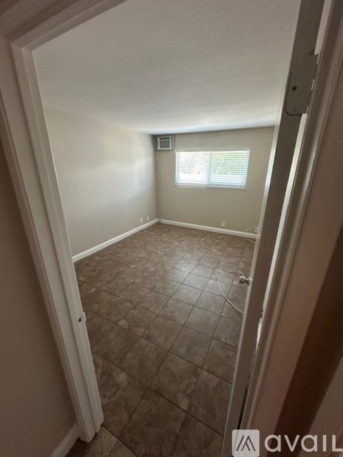 A room with tiled flooring and a window with blinds.