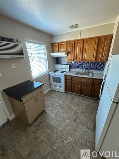 A kitchen with a white stove, white refrigerator, and brown cabinets.