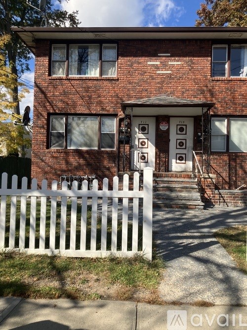 A red brick house with a white picket fence in front.