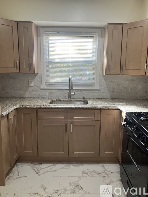 A kitchen with brown cabinets and a marble countertop.