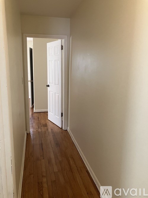 A hallway with a white door and wooden floor.