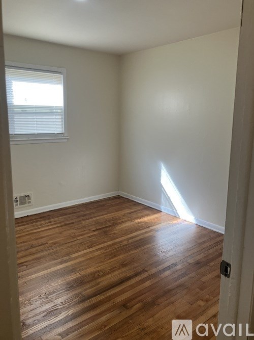 A room with wooden flooring and a window with blinds.