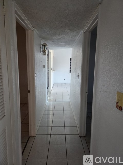 A long white hallway with a light fixture on the wall.