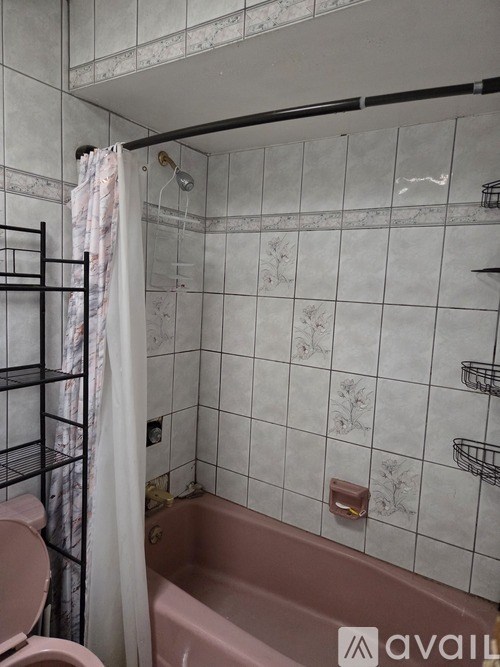 A bathroom with a pink tub and a toilet.